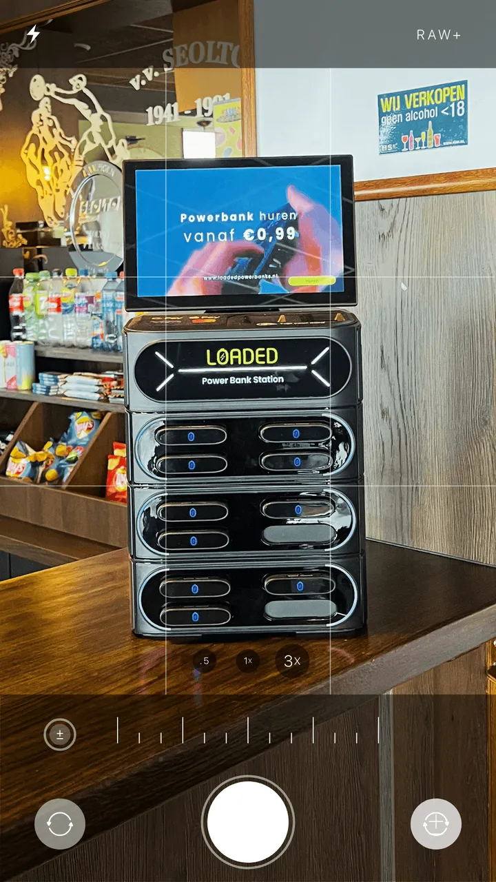 Loaded 12-slot powerbankstation op de bar van een sportkantine, gefotografeerd met een telefoon